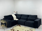Modern black corner sofa with plush cushions in a minimalist living room, cowhide rug and gold bar cart