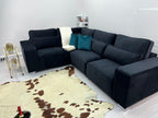 Modern black corner sofa with teal cushions, cowhide rug, and gold bar cart in living room
