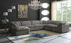 Modern living room with large cream modular corner sofa, ottoman, chandelier, and abstract rug