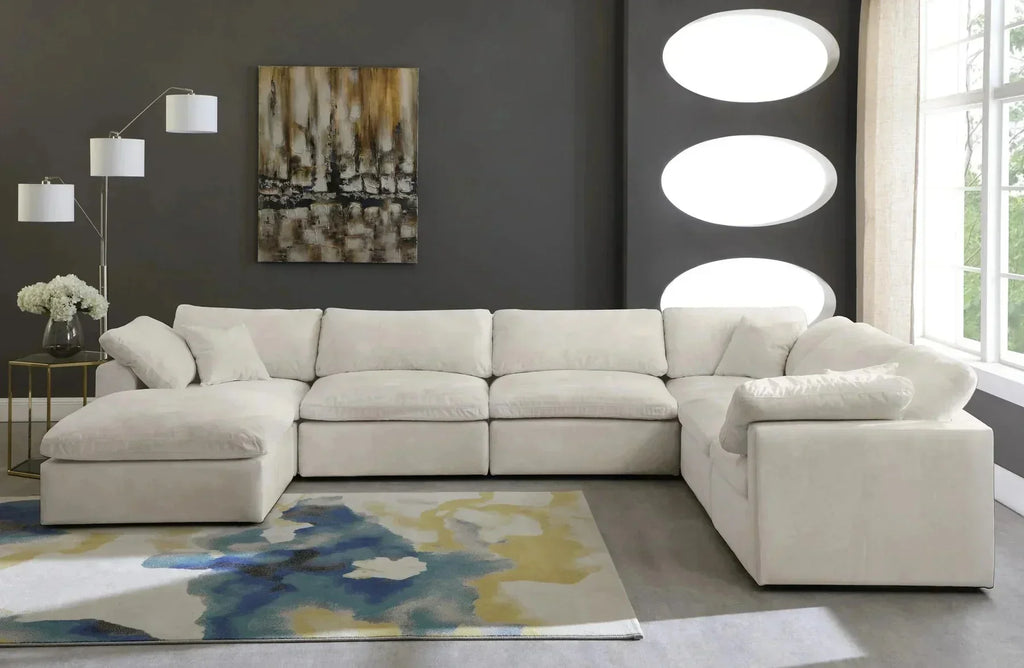 Cream modular corner sofa with footstool in modern living room, abstract rug, and wall art.