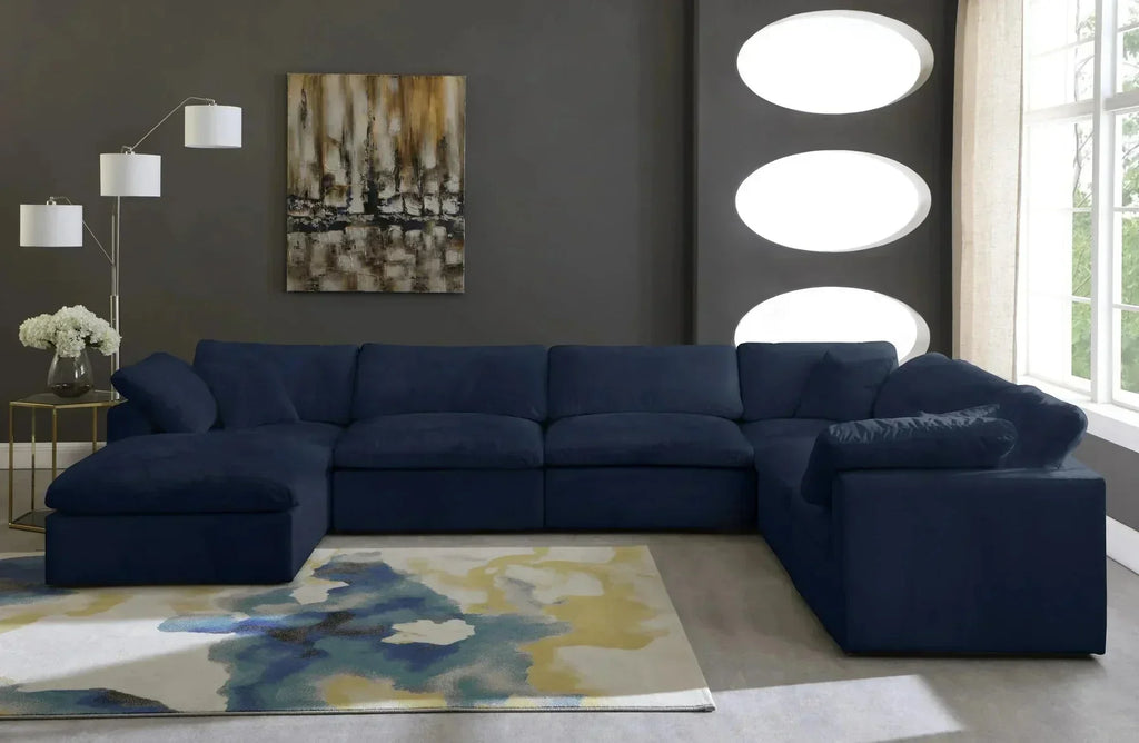 Modern living room with a navy blue modular corner sofa, cream footstool, and abstract rug