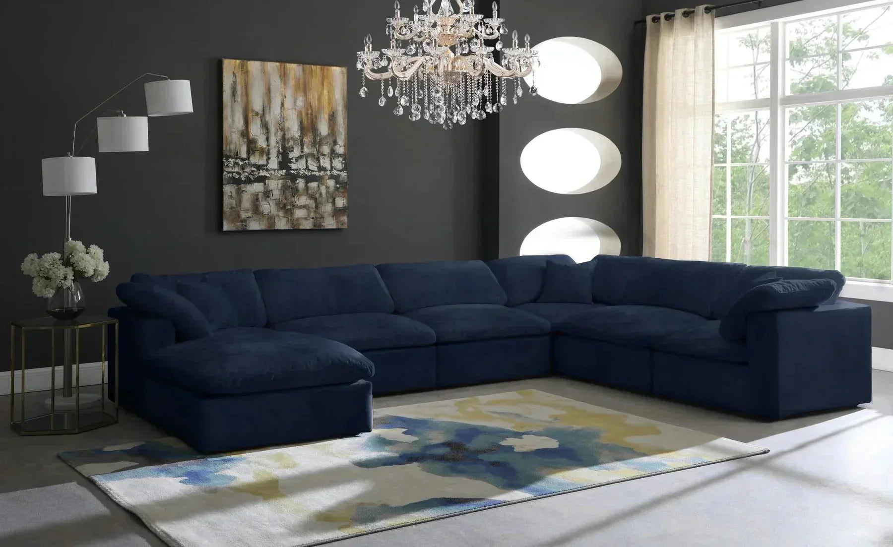 Large navy blue modular corner sofa in modern living room with chandelier and abstract rug