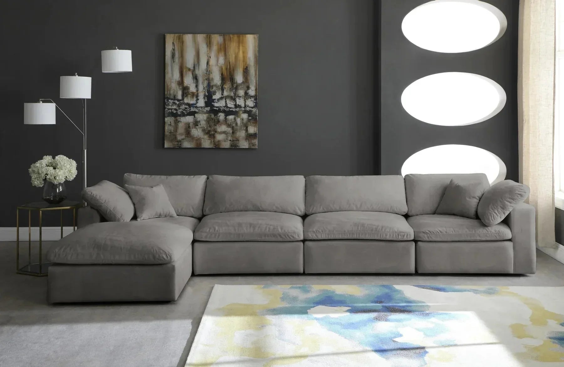 Cream modular corner sofa with chaise in modern living room, abstract rug and dark walls