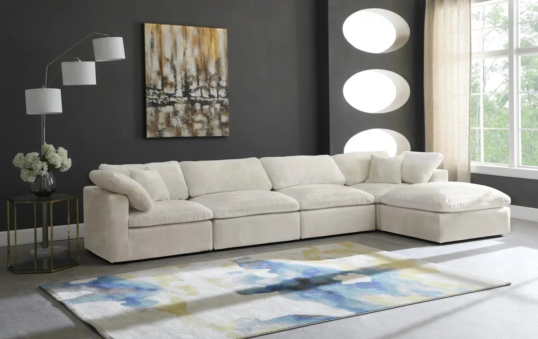 Cream modular corner sofa with plush cushions in a modern living room with grey walls and abstract decor.