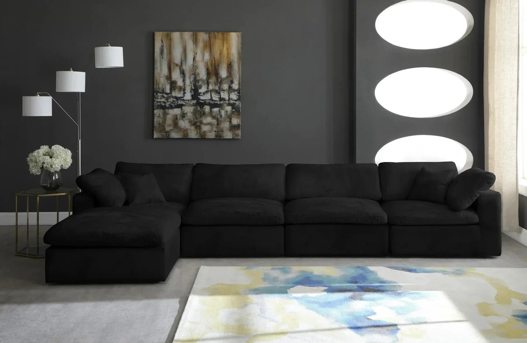 Large black corner modular sofa in modern living room with abstract painting and floor lamp