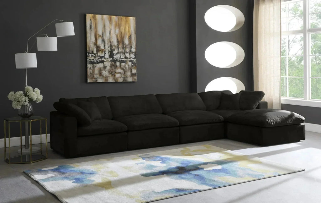 Modern living room with black modular corner sofa, abstract rug, floor lamp, and wall art.