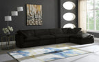 Modern living room with black modular corner sofa, abstract rug, floor lamp, and wall art.