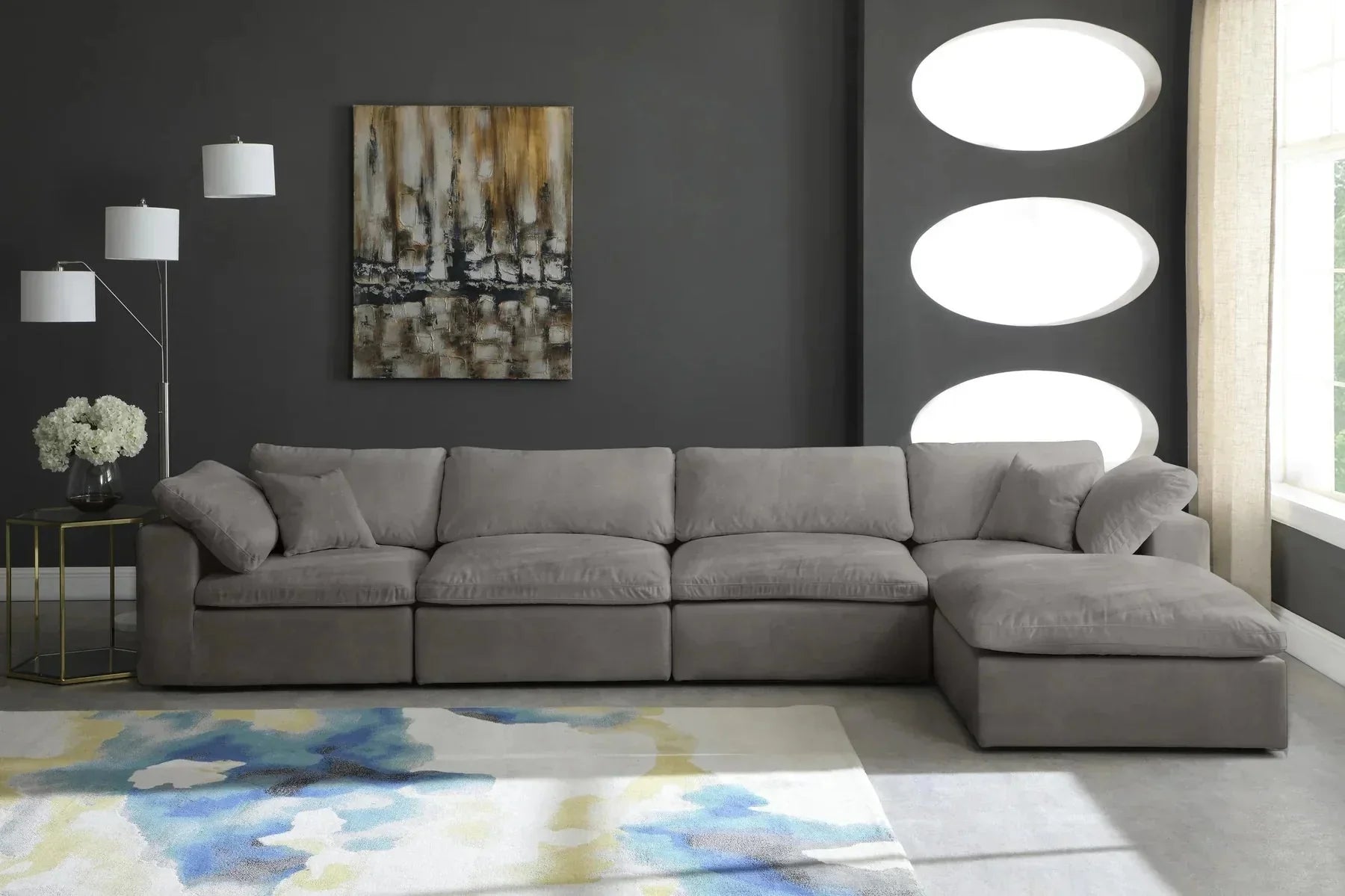 Modern living room with large grey modular corner sofa, abstract rug, and dark accent wall