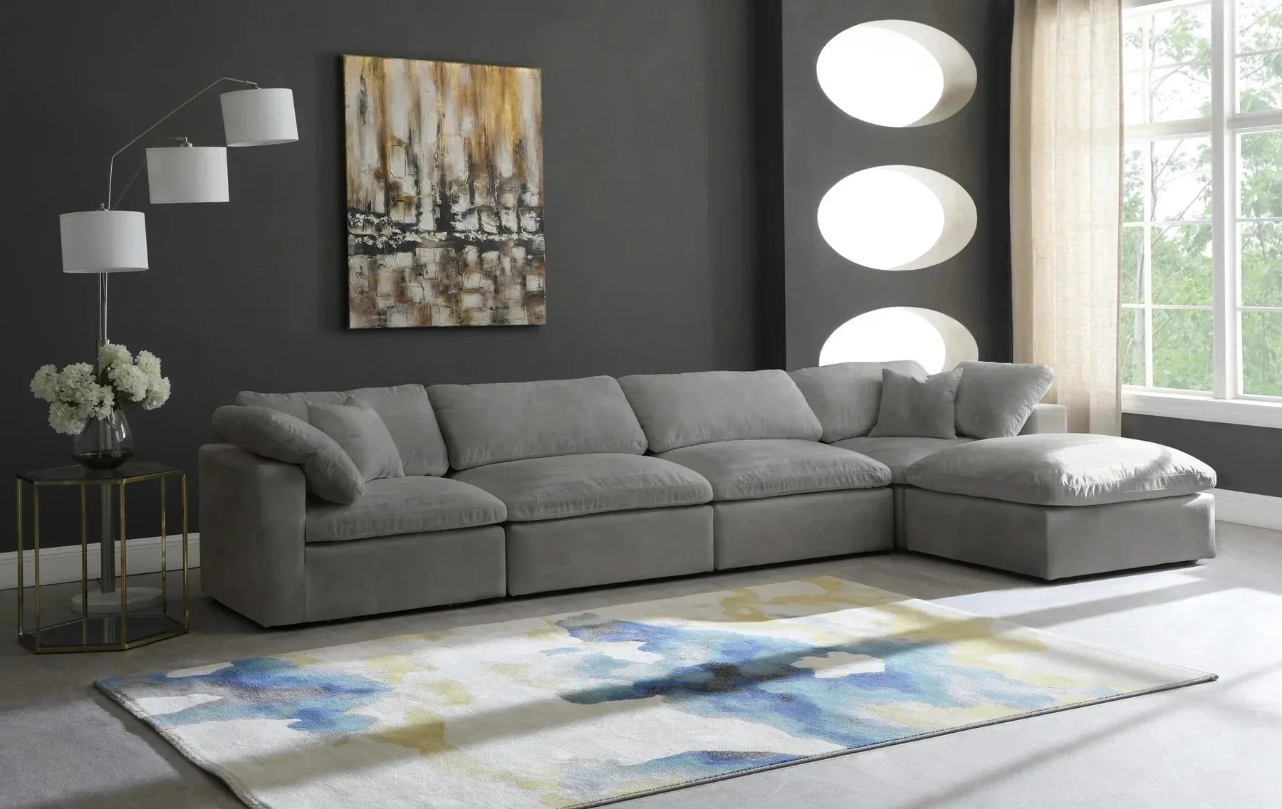 Modern living room with large grey modular corner sofa, abstract rug, and dark accent wall.