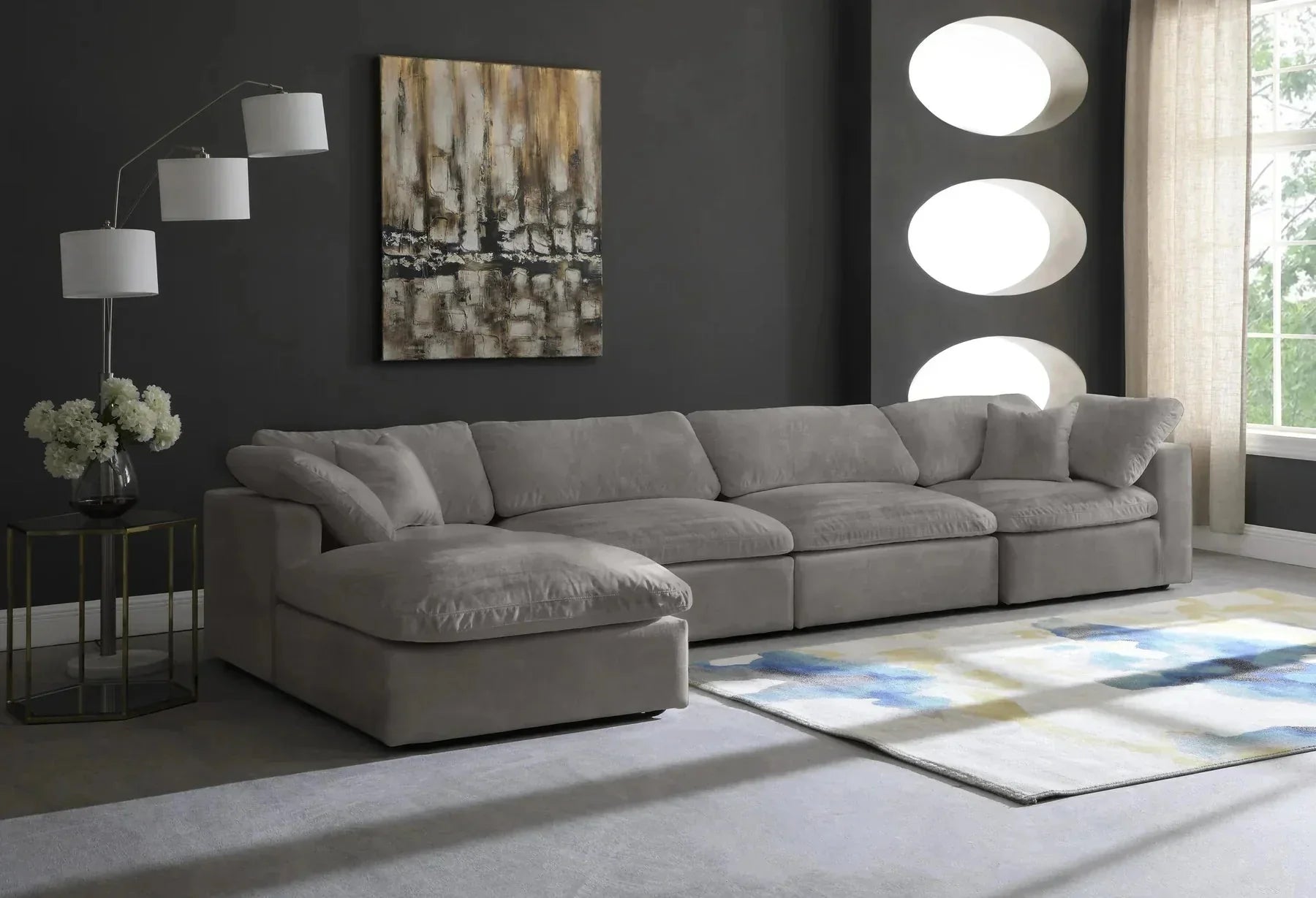 Modern cream modular corner sofa with chaise in a stylish living room with dark walls, abstract art, and a patterned rug