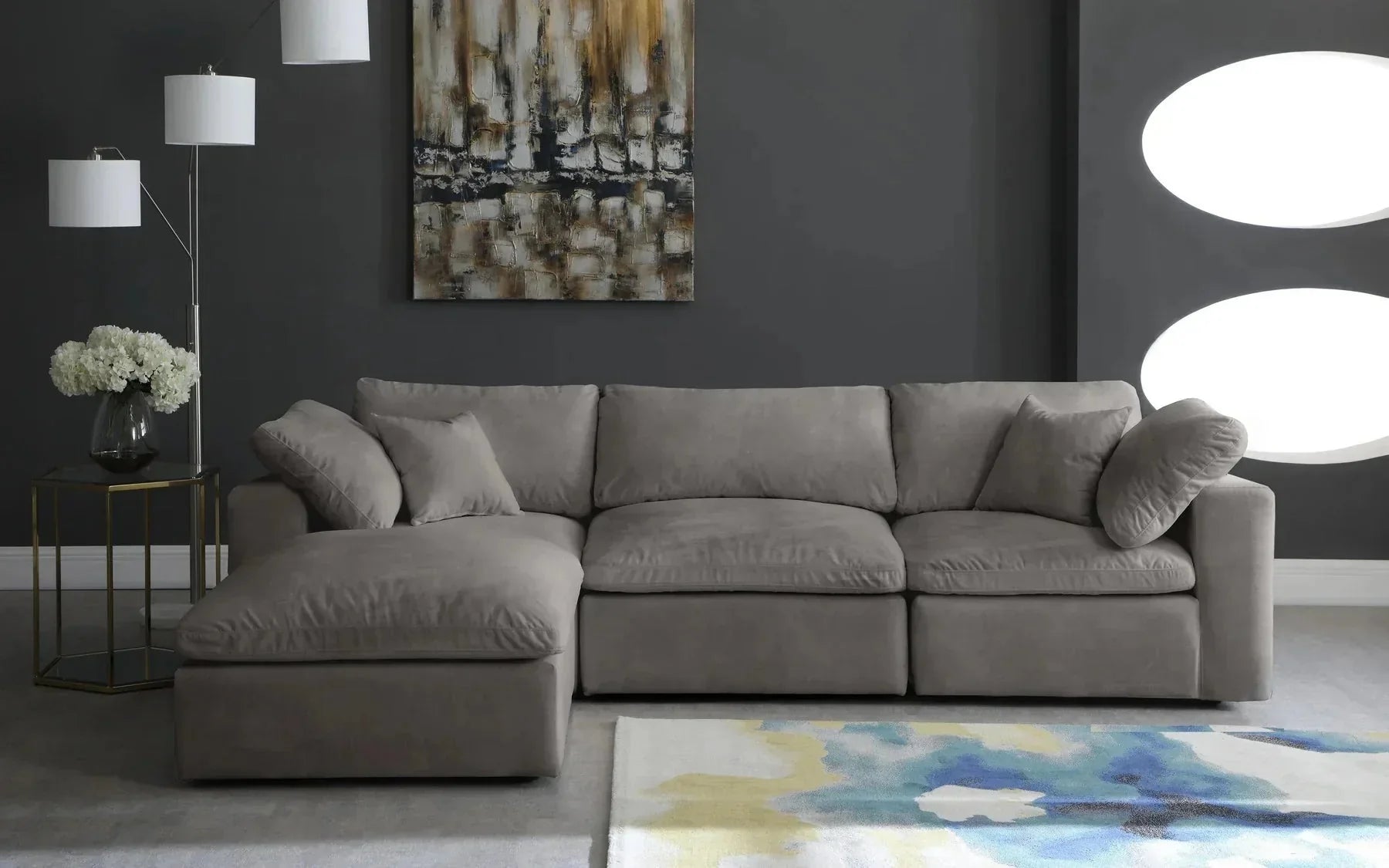 Cream modular corner sofa with footstool in modern living room, abstract rug, and wall art