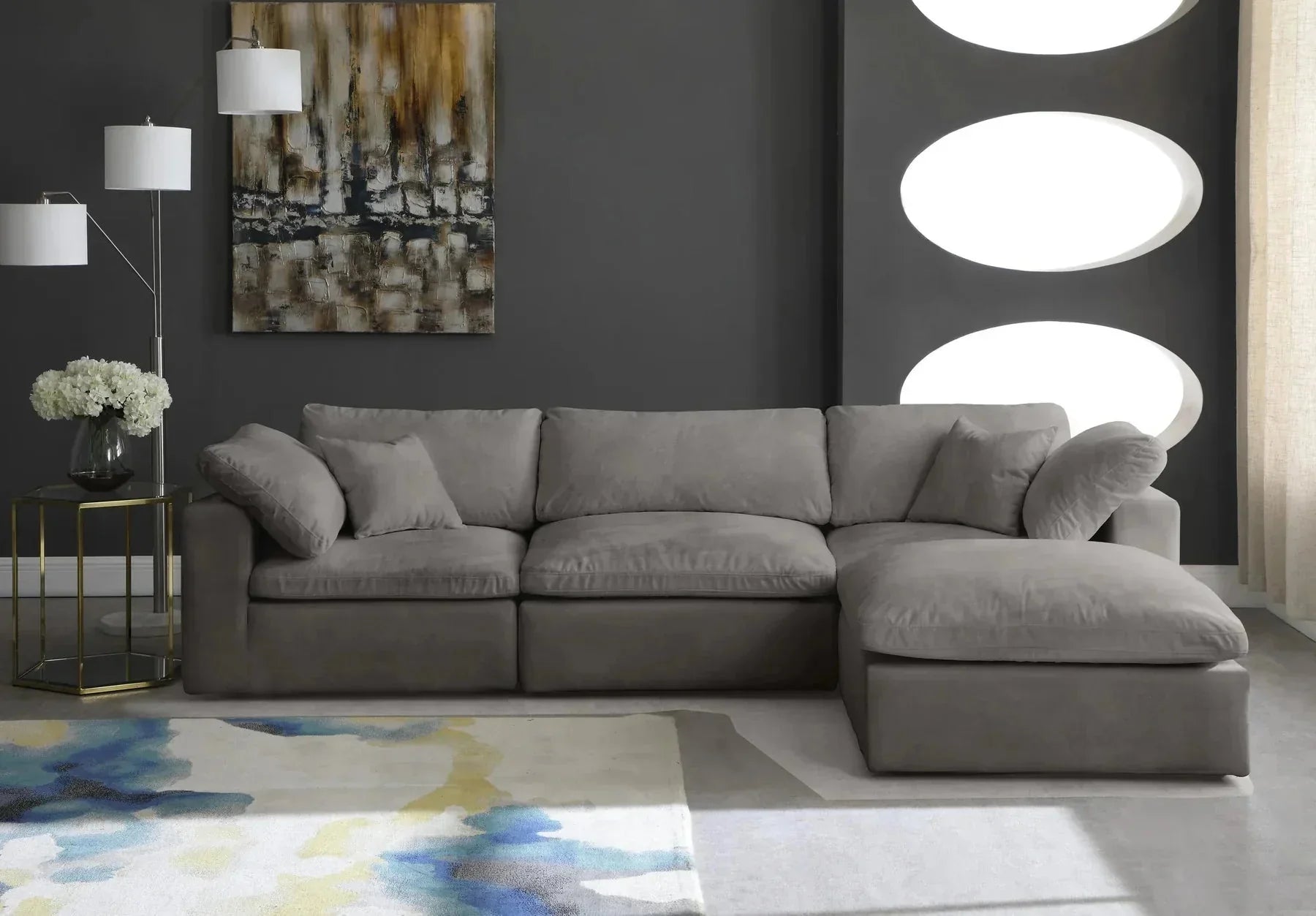Modern living room with a grey modular corner sofa, abstract rug, and dark accent wall.