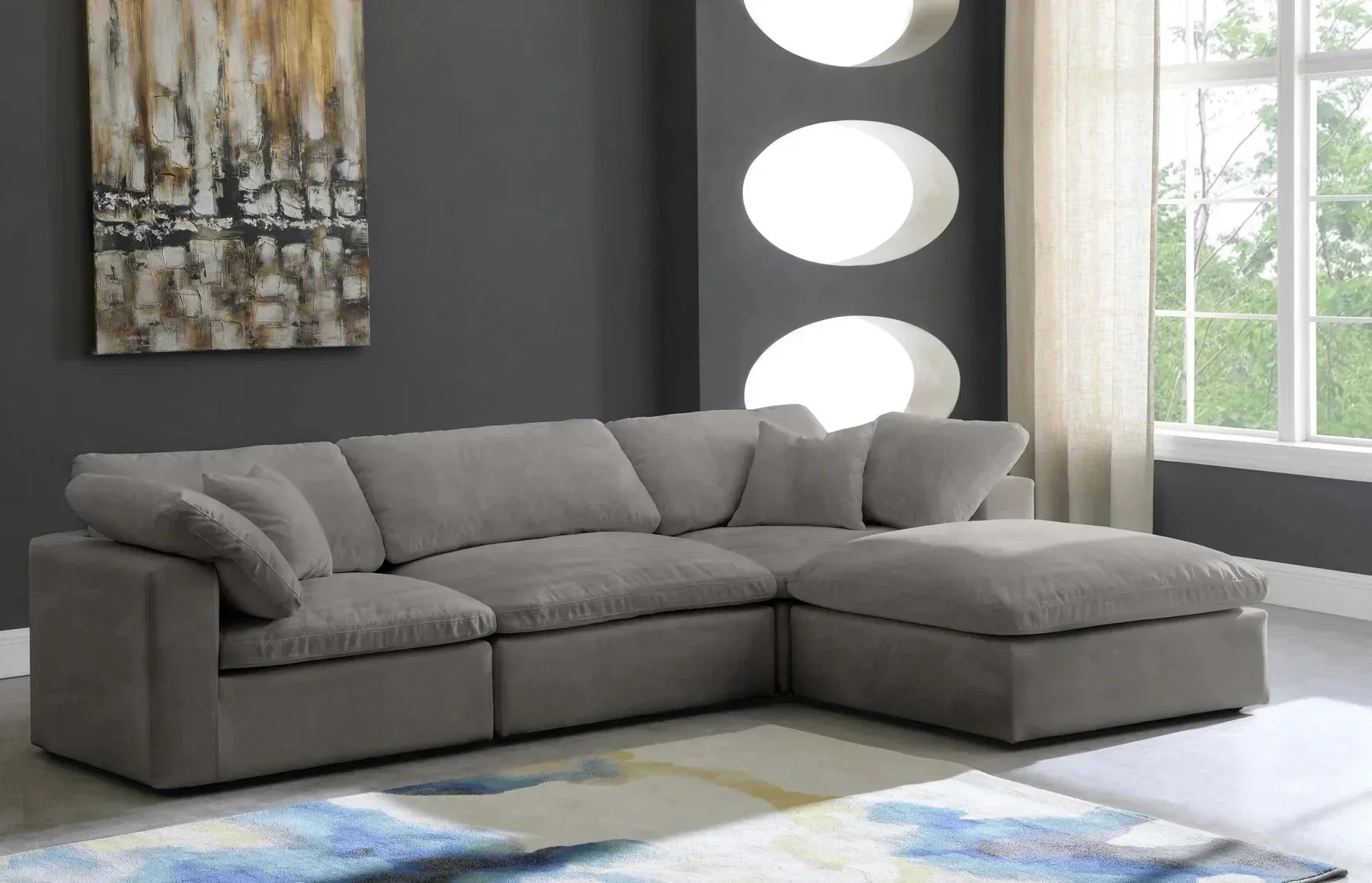 Modern grey modular corner sofa with chaise in stylish living room, abstract wall art, and large windows
