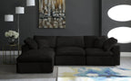 Modern black modular sofa with chaise in a stylish living room, abstract wall art, and geometric rug.