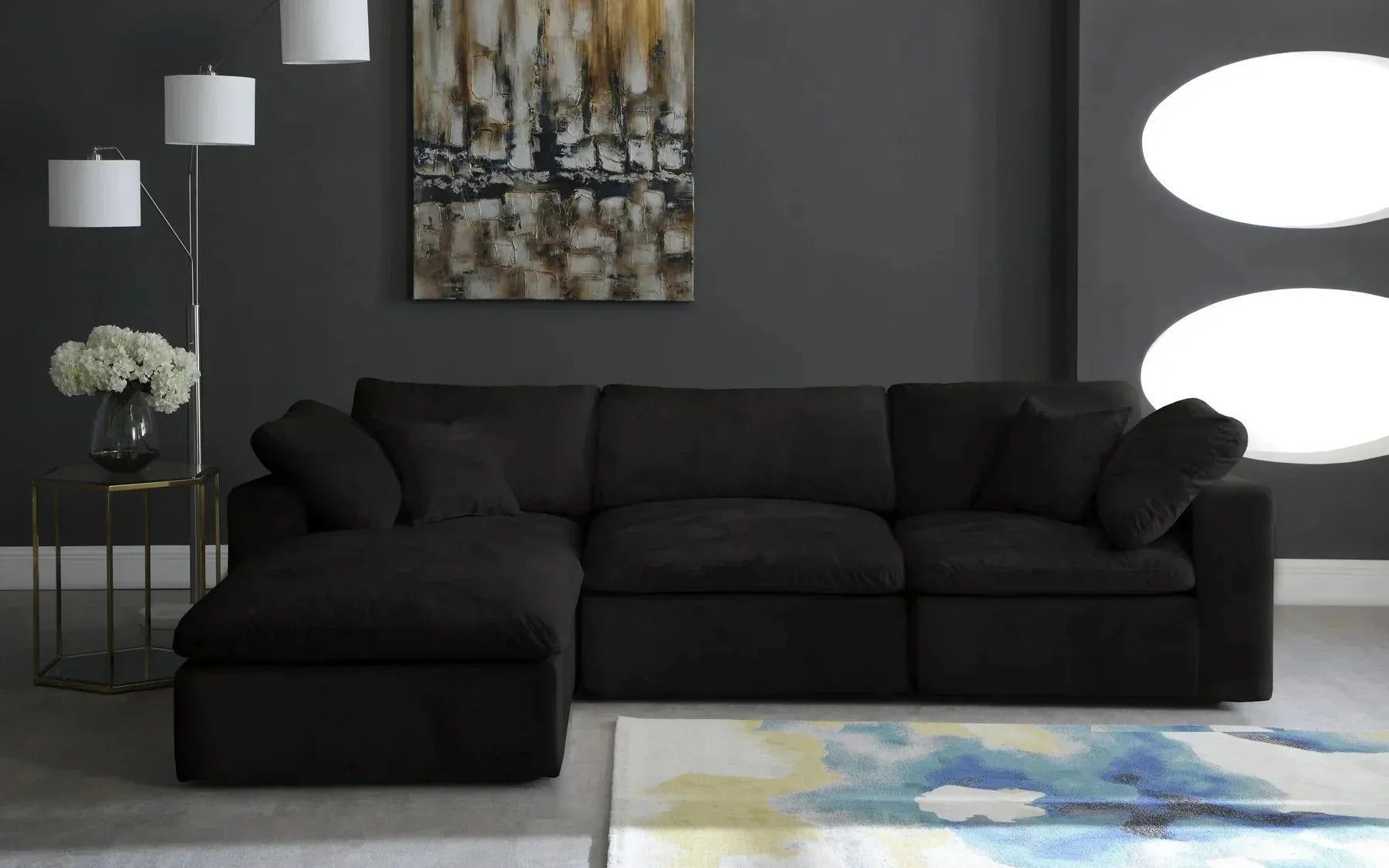 Modern black modular sofa with chaise in a stylish living room, abstract wall art, and geometric rug.