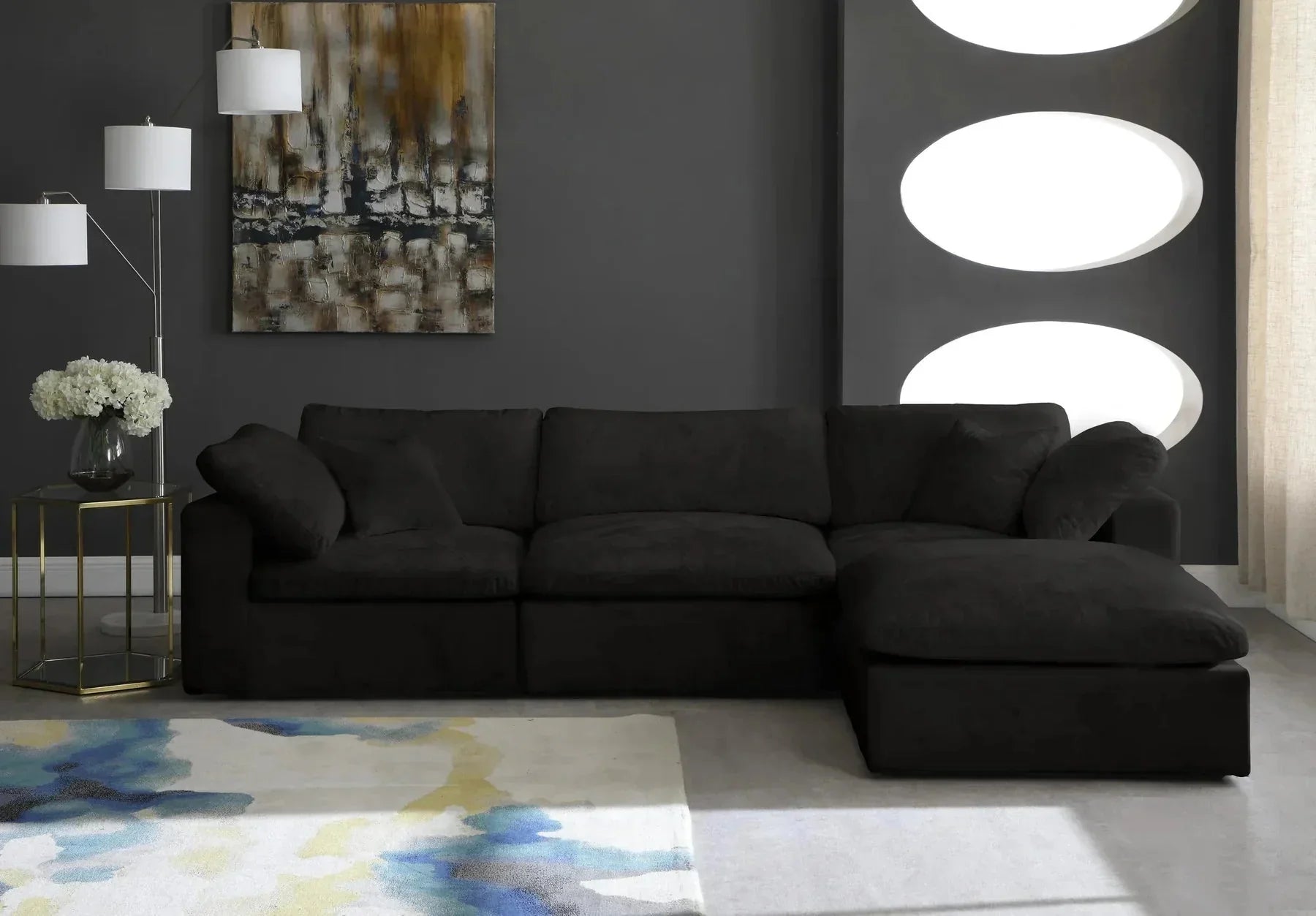 Modern black modular sofa with chaise in stylish living room, abstract art, and large rug