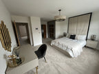 Contemporary bedroom with cream upholstered bed, tall deluxe headboard, and gold accents