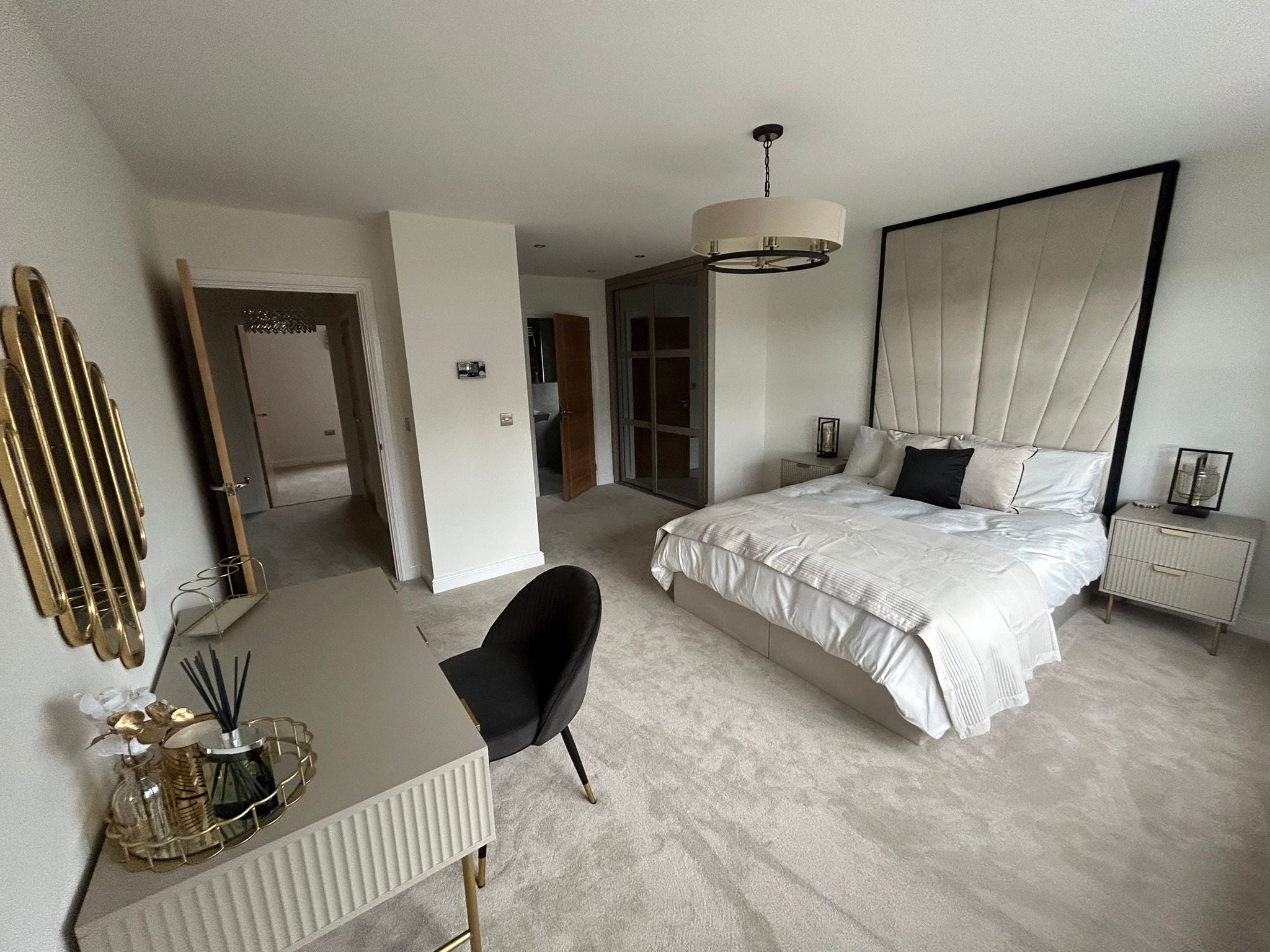 Contemporary bedroom with cream upholstered bed, tall deluxe headboard, and gold accents