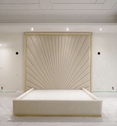 Luxury cream bed with gold outline and tall modern headboard in a minimalist bedroom