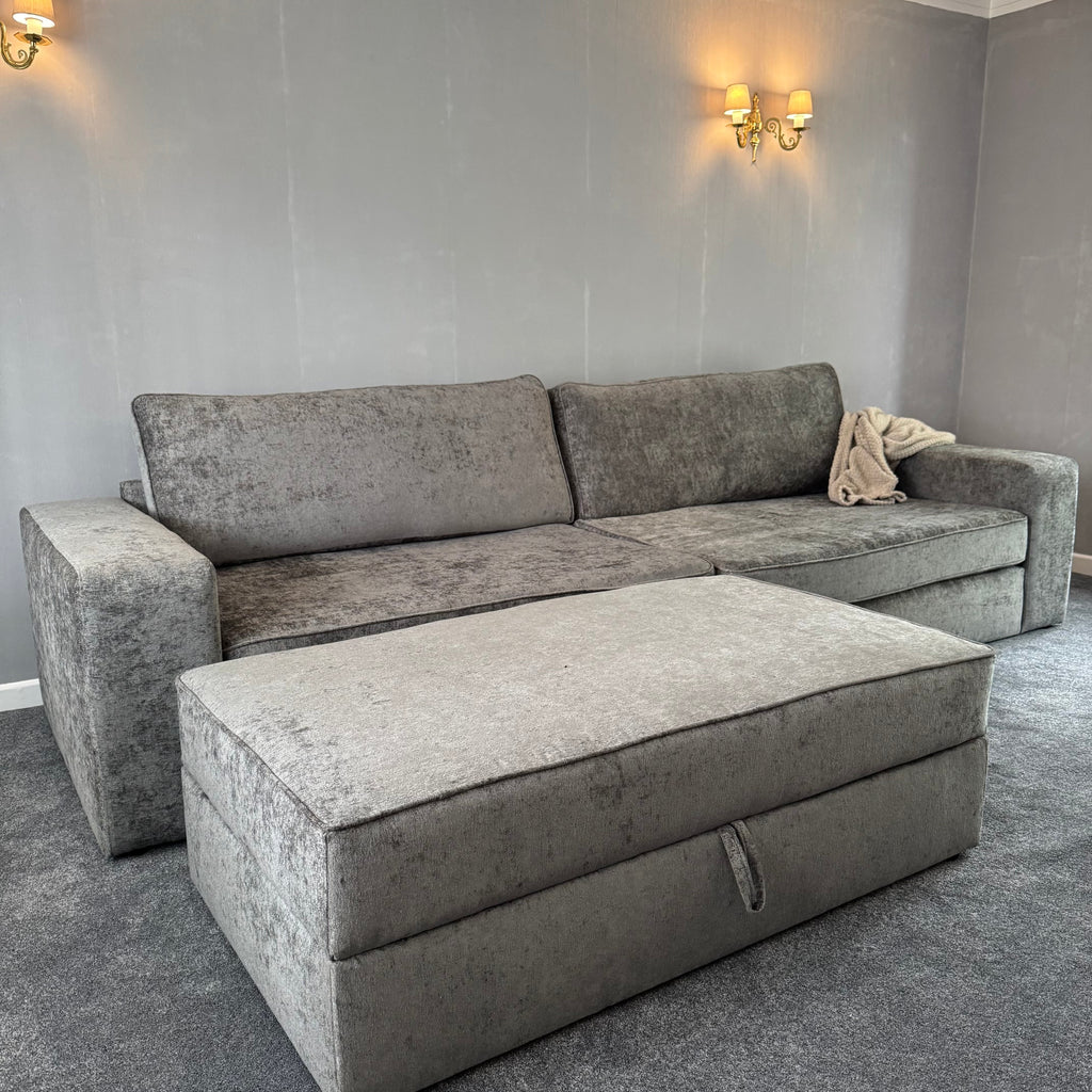 Large grey fabric sofa with matching storage footstool in a modern living room