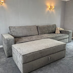 Large grey fabric sofa with matching storage footstool in a modern living room