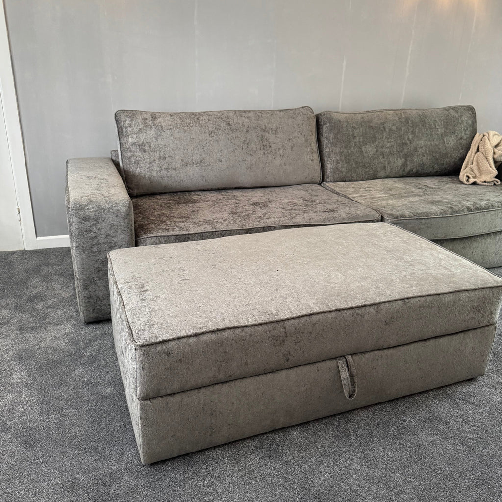 Large grey sofa with matching storage footstool in a modern living room