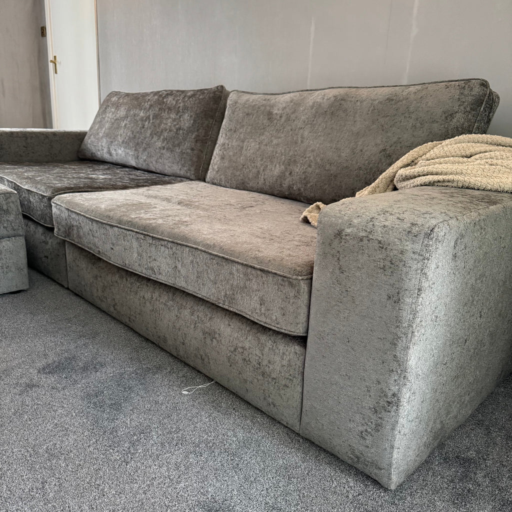 Large grey fabric sofa with storage footstool in a modern living room