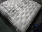 Emperor size, tufted white mattress wrapped in protective plastic on carpeted floor