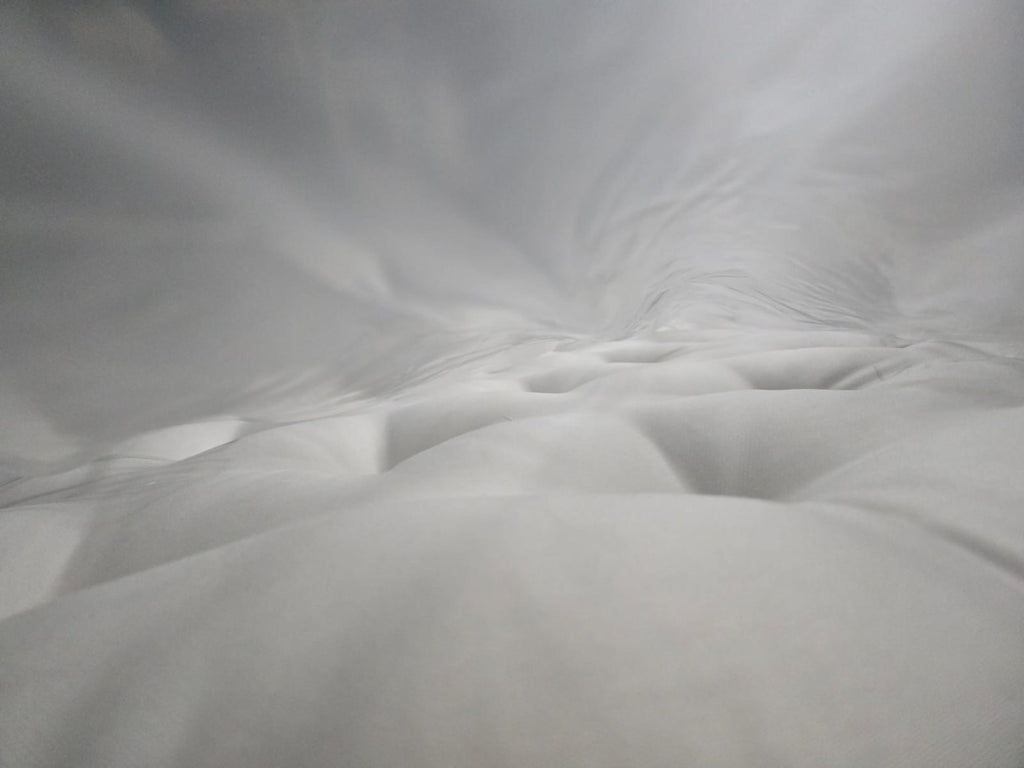 Close-up of a plush, tufted white mattress surface with soft fabric texture