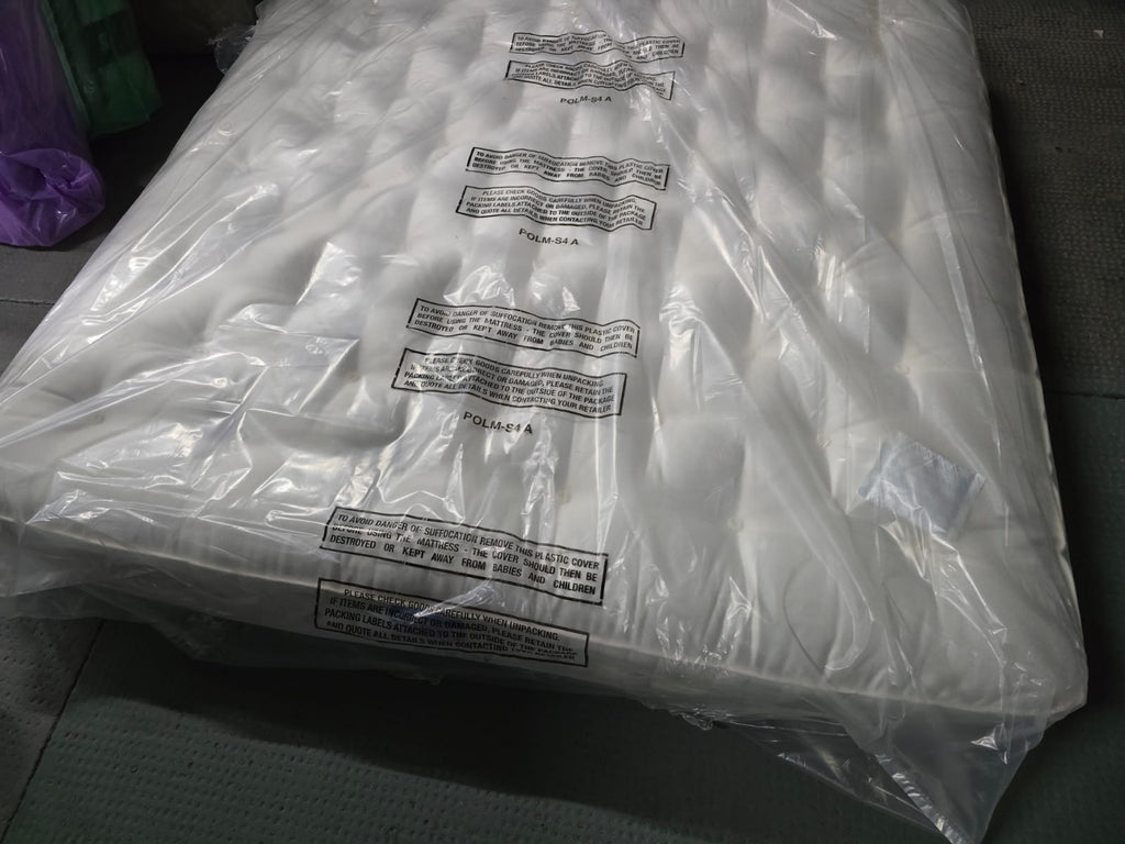 Emperor size luxury mattress in protective plastic wrap, tufted surface, on showroom floor
