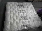 Emperor size white mattress in protective plastic wrap on a grey floor