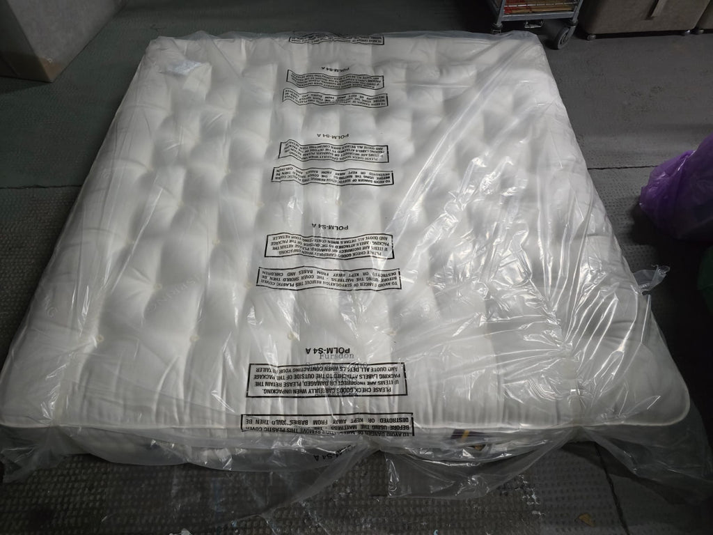Emperor size luxury mattress with tufted white surface in protective plastic packaging