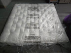 Emperor size luxury mattress with tufted white surface in protective plastic packaging