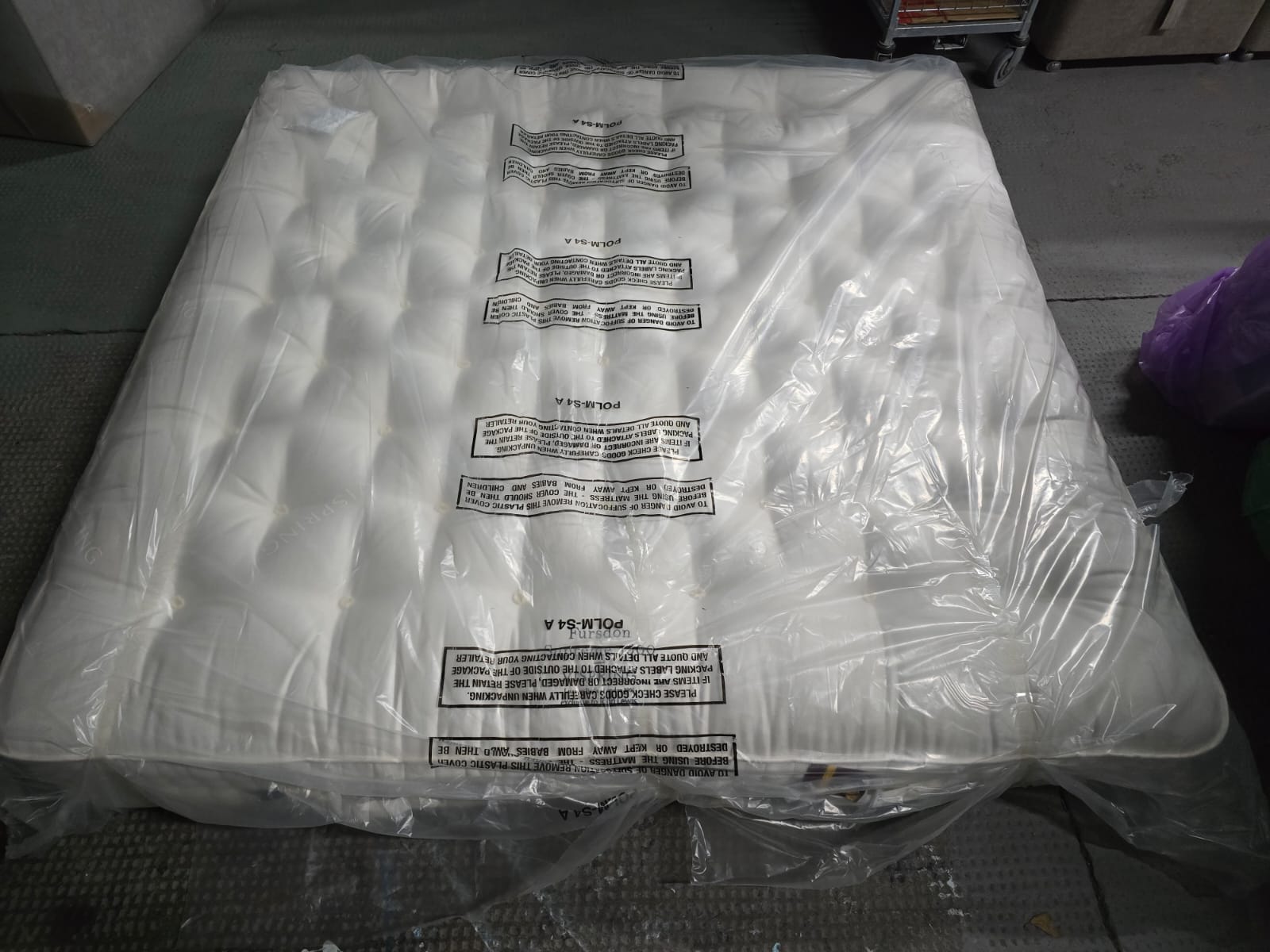 Emperor size luxury mattress with tufted white surface in protective plastic packaging