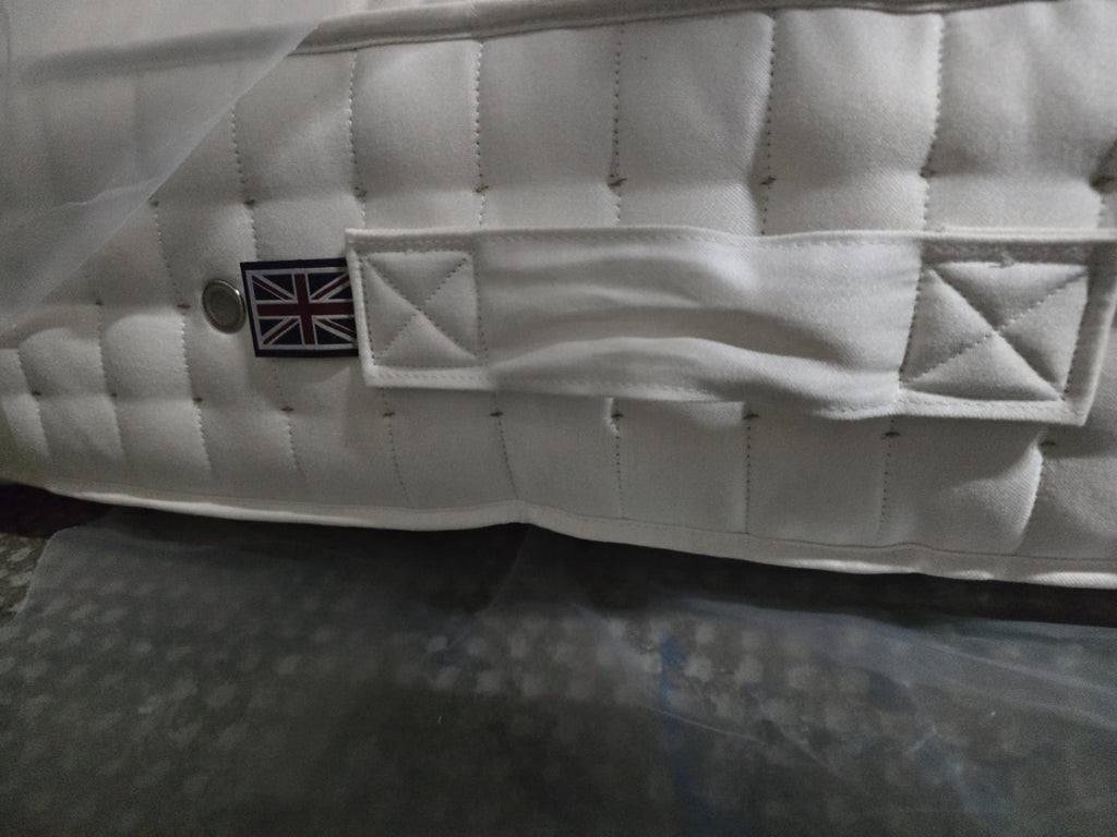 Close-up of luxury white mattress with quilted pattern, fabric handle, and UK flag label