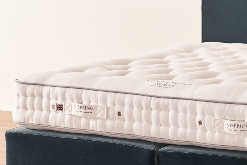 Emperor size luxury mattress with tufted white surface and label on a bed base