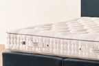 Emperor size luxury mattress with tufted white surface and label on a bed base