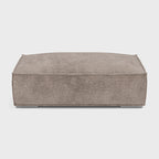 Taupe fabric double corner footstool on white background, modern rectangular design
