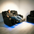 Modern black leather electric recliner sofa set with blue LED lighting and a person relaxing