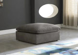 Grey feather-filled footstool in a modern living room with grey walls and natural light.