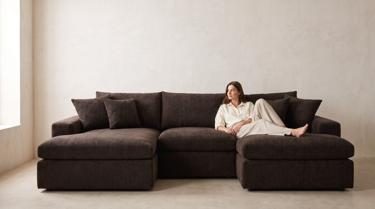 Lucca double chaise cinema sofa in Double Espresso chenille with a model relaxing on the chaise