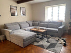 Modern grey modular corner sofa in bright living room with geometric rug and coffee table