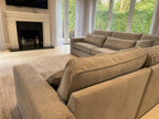 Grey modular corner sofa in a modern living room with large windows and fireplace