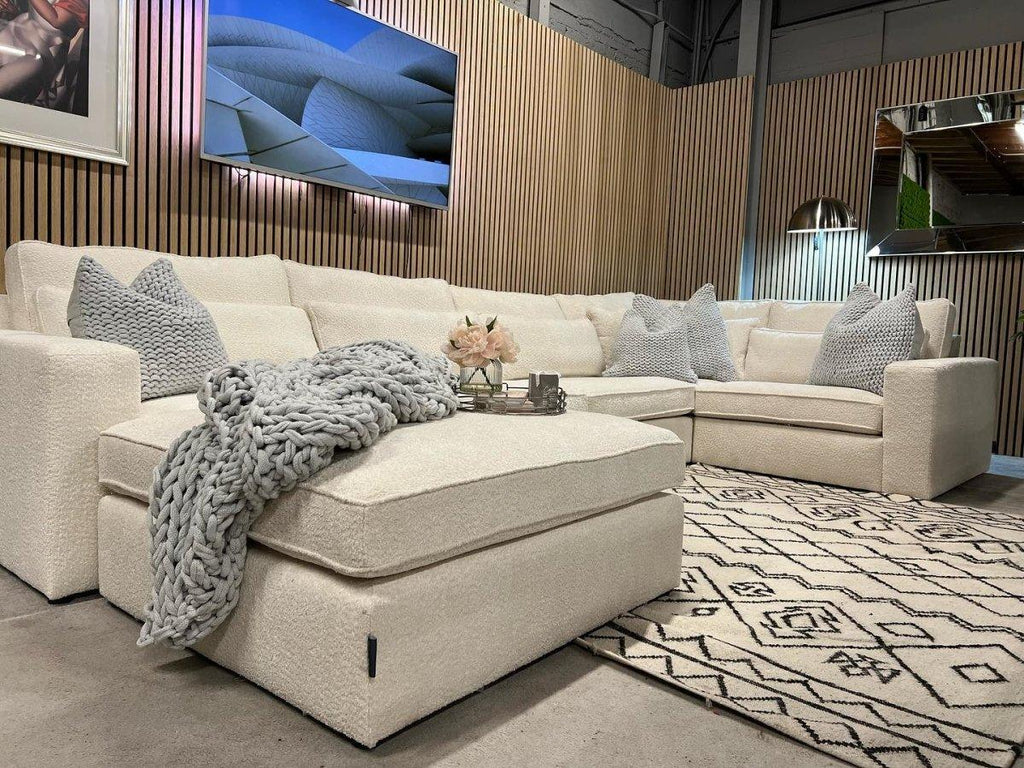 Cream boucle modular footstool in modern living room with matching sectional sofa and knit throw blanket
