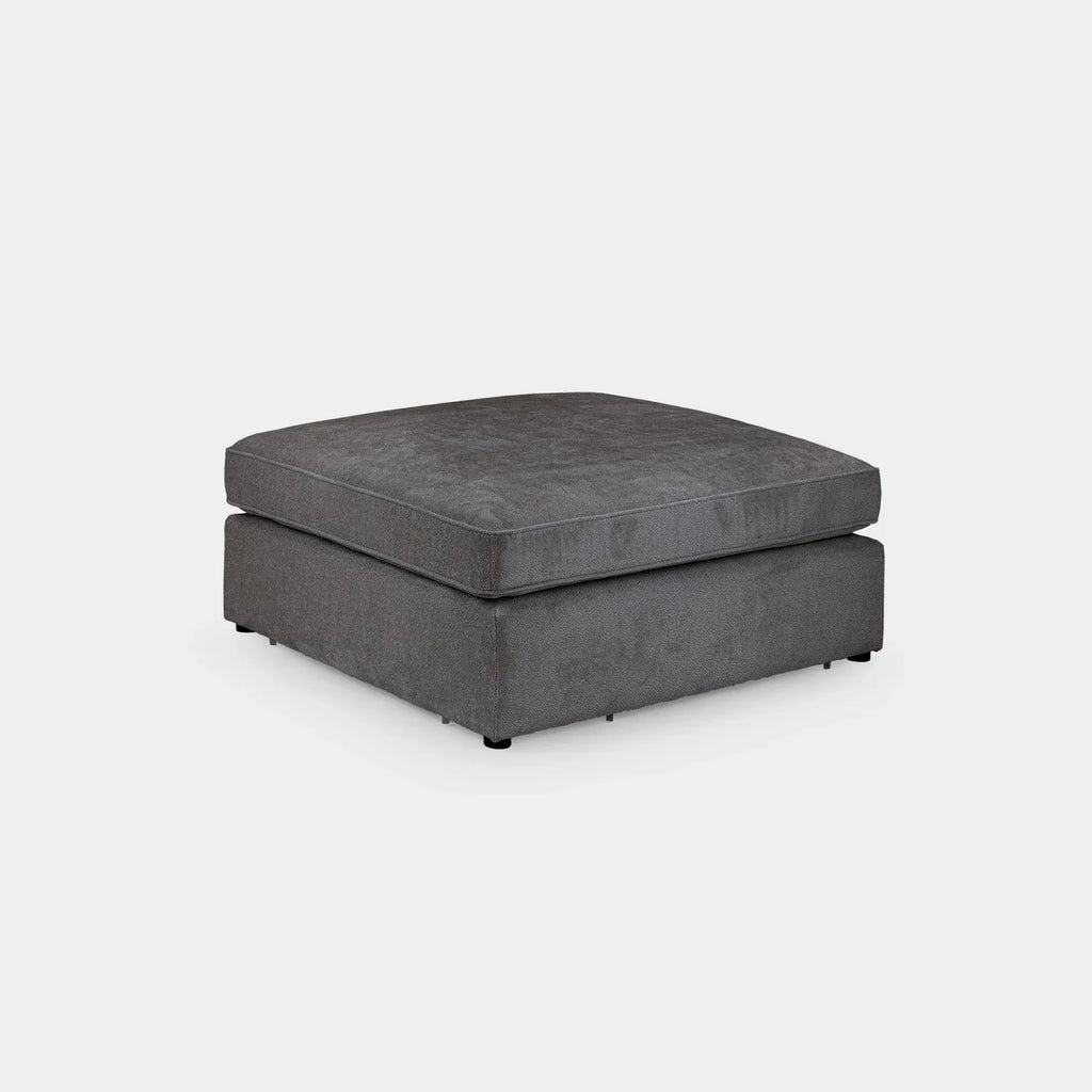 Modern grey fabric footstool ottoman with clean lines on a plain background