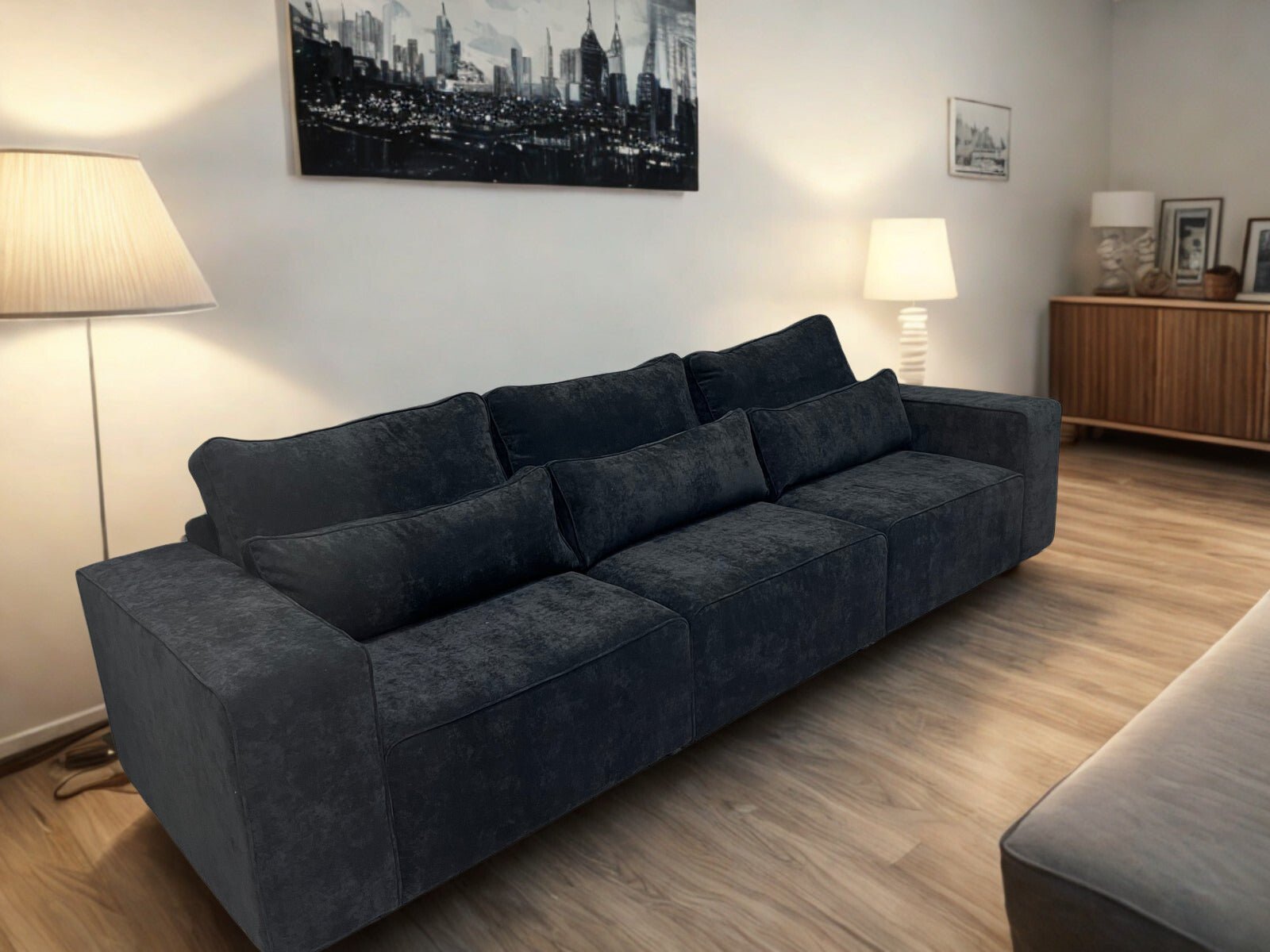 Large black modular sofa in a modern living room with wooden flooring and contemporary decor
