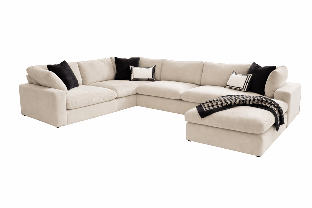 Large beige U-shaped modular sofa with black and white accent pillows and throw blanket