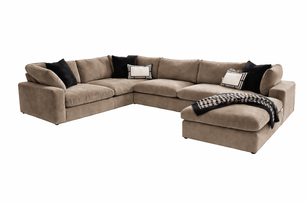 Large U-shaped beige modular sofa with footstool, black and white cushions, and throw blanket