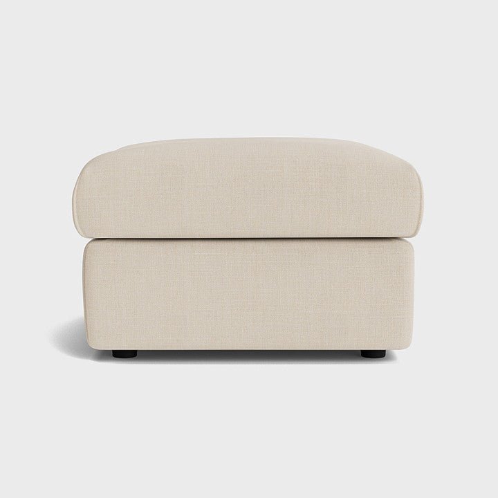 Cream fabric ottoman footstool with clean lines on a white background