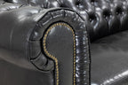 Black chesterfield leather sofa armrest with button tufting and studded trim close-up